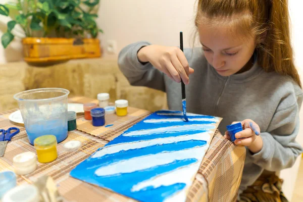 少女は青いグワッシュの段ボールを描き抽象的な背景を作り自宅のキッチンに座り — ストック写真