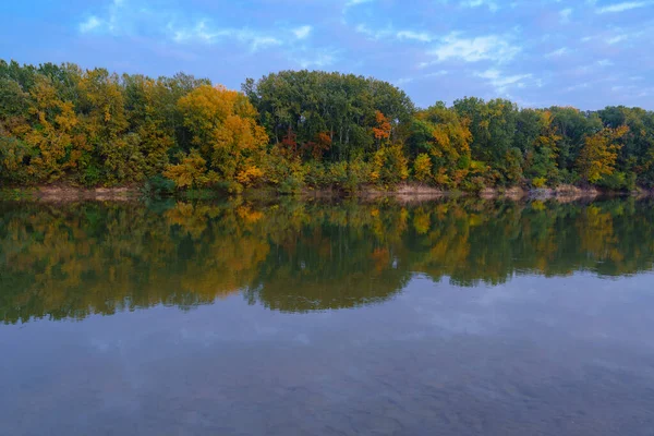 Akşamları renkli sonbahar ormanı manzarası. Nehir ve mavi gökyüzü yakınlarındaki ağaçlar.