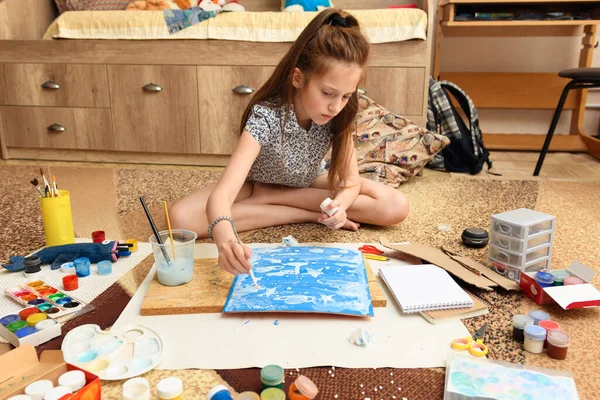 女の子は家で絵を描き紙や絵具や筆から創造的な作品を作り — ストック写真