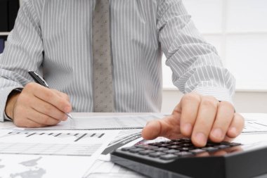 İş dünyası konsepti - iş adamının çalışma masası yakın görünümü, mali raporları kontrol etmesi, yazması ve sayması