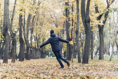 Parkta koşan ve sonbaharın tadını çıkaran bir çocuk. Sarı yapraklı güzel bir doğa.