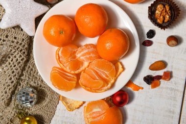 Noel ya da tatil süslemeleri için tatlı yemek arkaplanı - çikolata şekerlemeleri, mandalinalar, fındıklar ve kuru meyveler beyaz ahşap üzerinde