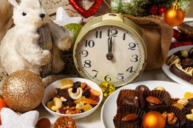 Noel ya da tatil süslemeleri için tatlı yemek arkaplanı - çikolata şekerlemeleri, mandalinalar, fındıklar ve kuru meyveler beyaz ahşap üzerinde