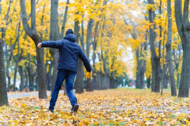 Parkta koşan ve sonbaharın tadını çıkaran bir çocuk. Sarı yapraklı güzel bir doğa.