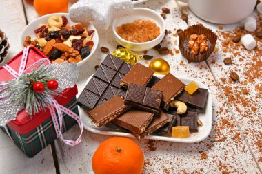 Mutlu noeller ya da yeni yıl dekorasyonu için tatlı yemek arka planı - çikolata şekerlemeleri, mandalinalar, kurabiyeler, marşmelov ve beyaz ahşap üzerine kakao latte