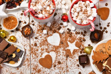 Mutlu noeller ya da yeni yıl dekorasyonu için tatlı yemek arka planı - çikolata şekerlemeleri, mandalinalar, kurabiyeler, marşmelov ve beyaz ahşap üzerine kakao latte