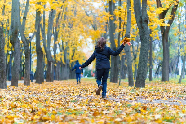 소녀와 소년은 공원을 뛰어다니며 아름다운 가을을 즐긴다 — 스톡 사진