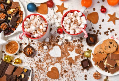 Mutlu noeller ya da yeni yıl dekorasyonu için tatlı yemek arka planı - çikolata şekerlemeleri, mandalinalar, kurabiyeler, marşmelov ve beyaz ahşap üzerine kakao latte