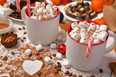 Mutlu noeller ya da yeni yıl dekorasyonu için tatlı yemek arka planı - çikolata şekerlemeleri, mandalinalar, kurabiyeler, marşmelov ve beyaz ahşap üzerine kakao latte