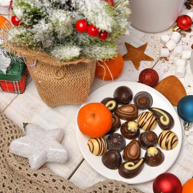 Mutlu noeller ya da yeni yıl dekorasyonu için tatlı yemek arka planı - çikolata şekerlemeleri, mandalinalar, kurabiyeler, marşmelov ve beyaz ahşap üzerine kakao latte