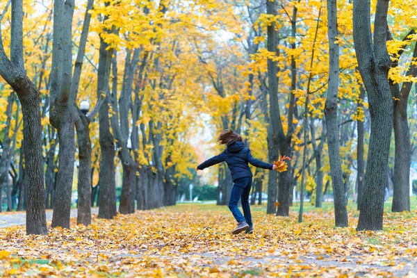 一个女孩在公园里跑来跑去 享受着秋天 美丽的大自然 有着黄叶 — 图库照片