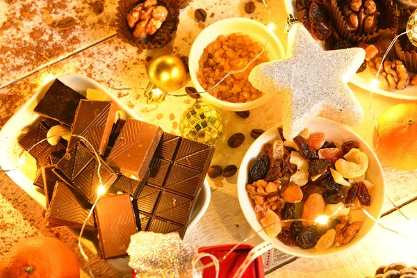 甘い食べ物のトップビューの背景陽気なクリスマスや夜の照明で新年の休日の装飾 チョコレートキャンディー みかん 白い木のクッキー — ストック写真