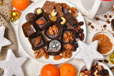 Mutlu noeller ya da yeni yıl dekorasyonu için tatlı yemek üst görünümü - çikolata şekerler, mandalinalar, beyaz ahşap üzerinde kurabiyeler