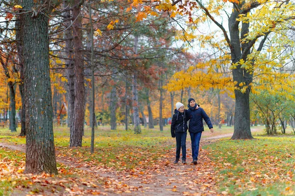 공원을 거닐고 소녀와 소년은 노란색 아름다운 가을을 즐긴다 — 스톡 사진
