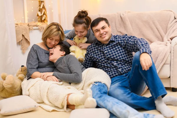 一个家庭坐在沙发上的画像 四个人在一起玩乐 — 图库照片