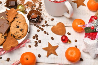 Mutlu noeller ya da yeni yıl dekorasyonu için tatlı yemek arka planı - çikolata şekerlemeleri, mandalinalar, kurabiyeler, marşmelov ve beyaz ahşap üzerine kakao latte