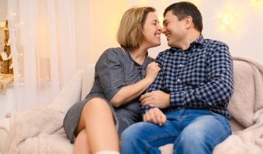 Evdeki kanepede oturan yetişkin bir çiftin portresi..