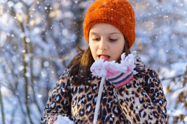 Çocuk kar yer ve kış ormanlarında eğlenir. Parlak güneş ışığı ve kardaki gölgeler. Güzel doğa..