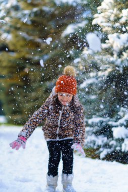 Çocuk kar kusar ve kış ormanlarında oynar, parlak karlı köknar ağaçları, güzel doğa.
