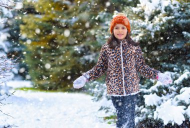 Kışın ormanda koşan ve karla oynayan çocuk, parlak karlı köknar ağaçları, güzel doğa..