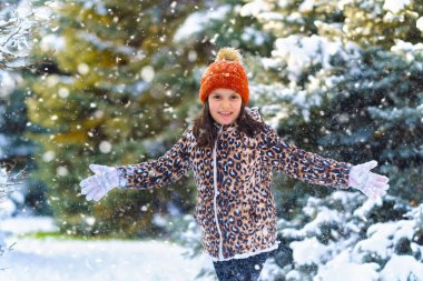 Kışın ormanda koşan ve karla oynayan çocuk, parlak karlı köknar ağaçları, güzel doğa..
