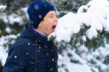 Genç çocuk kış ormanlarında kar yer, oynar ve yer, parlak karlı köknar ağaçları, güzel doğa.