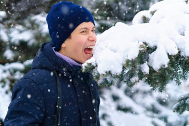 Genç çocuk kış ormanlarında kar yer, oynar ve yer, parlak karlı köknar ağaçları, güzel doğa.