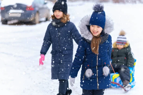 아이들은 겨울에 밖에서 썰매를 눈내리는 겨울을 즐겁게 보낸다 — 스톡 사진