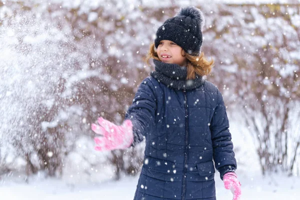 child girl playing with snow in winter outdoor and having fun on snowy winter