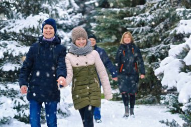 Aile kış ormanlarında yürüyor, iki ebeveyn ve iki çocuk, güzel doğa ve parlak karlı köknar ağaçları
