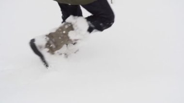 Bacakları küçük bir kızın kışın açık havada derin karda yürümesini yakından görüyor.