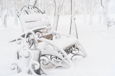 Kış şehri parkı, kar ve karla kaplı banklar.