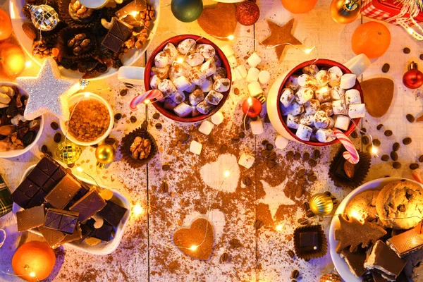 甘い食べ物のトップビューの背景メリークリスマスや夜のイルミネーションで新年の休日の装飾 白い木のチョコレートキャンディー みかん クッキー マシュマロ ココアラテ — ストック写真