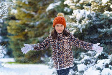 Kışın ormanda koşan ve karla oynayan çocuk, parlak karlı köknar ağaçları, güzel doğa..
