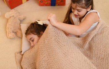 Kızlar yerde yatar, konuşur ya da uyur ve üzerlerini battaniyeyle örterler. Evin içi Noel ışıkları ve hediyelerle süslenir.