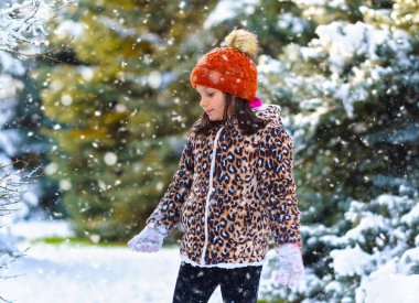 Kışın ormanda koşan ve karla oynayan çocuk, parlak karlı köknar ağaçları, güzel doğa..