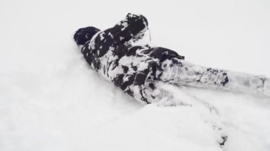 Adam kışın açık havada karda oynuyor ve bocalayıp duruyor.