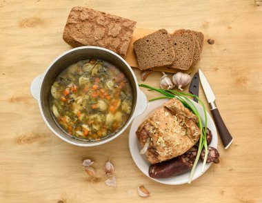 Tavada pişmiş et, çorba ve kan sosisi, yeşil soğan ve ahşap arka planda sarımsak, ev yemeği.