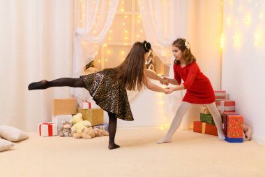 Kızlar oynar ve dans eder, ev dekore edilir şenlikli ışıklar ve hediyelerle