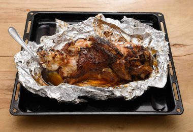 Fırında et ve kızarmış soğan, folyoda domuz eti ve ahşap arka plan, ev yemeği.