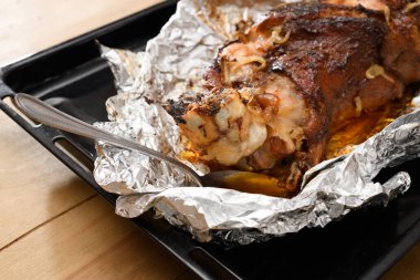 Fırında et ve kızarmış soğan, folyoda domuz eti ve ahşap arka plan, ev yemeği.