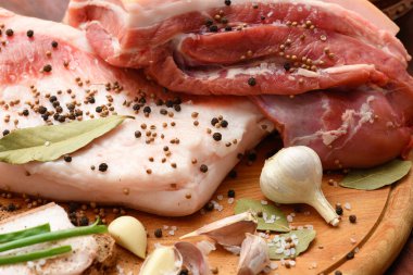 Kesme tahtasında tuzlu, baharatlı ve sarımsaklı çiğ domuz eti ve domuz yağı, koyu ahşap arka plan