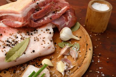 Kesme tahtasında tuzlu, baharatlı ve sarımsaklı çiğ domuz eti ve domuz yağı, koyu ahşap arka plan