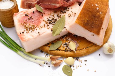 Kesme tahtasında tuzlu, baharatlı ve sarımsaklı çiğ domuz eti ve domuz yağı, beyaz arka plan.