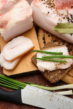 Kesme tahtasında tuzlu, baharatlı ve sarımsaklı çiğ domuz eti ve domuz yağı, koyu ahşap arka plan