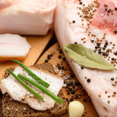 Kesme tahtasında tuzlu, baharatlı ve sarımsaklı çiğ domuz eti ve domuz yağı, koyu ahşap arka plan