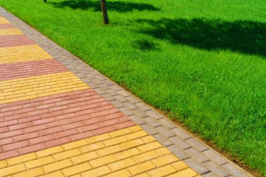 zemin olarak kaldırım taşları ve yeşil çimlerden yapılmış yürüyüş yolu, parlak güneş ışığı