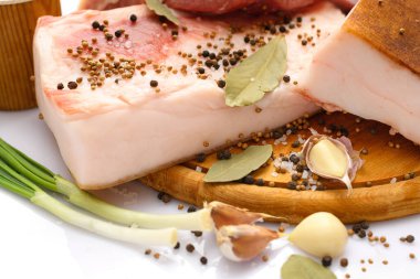 Kesme tahtasında tuzlu, baharatlı ve sarımsaklı çiğ domuz eti ve domuz yağı, beyaz arka plan.