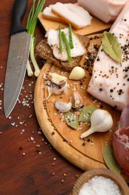 Kesme tahtasında tuzlu, baharatlı ve sarımsaklı çiğ domuz eti ve domuz yağı, koyu ahşap arka plan