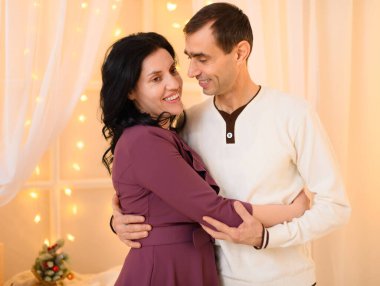 Evde ışıklarla dekore edilmiş yetişkin bir çiftin portresi.